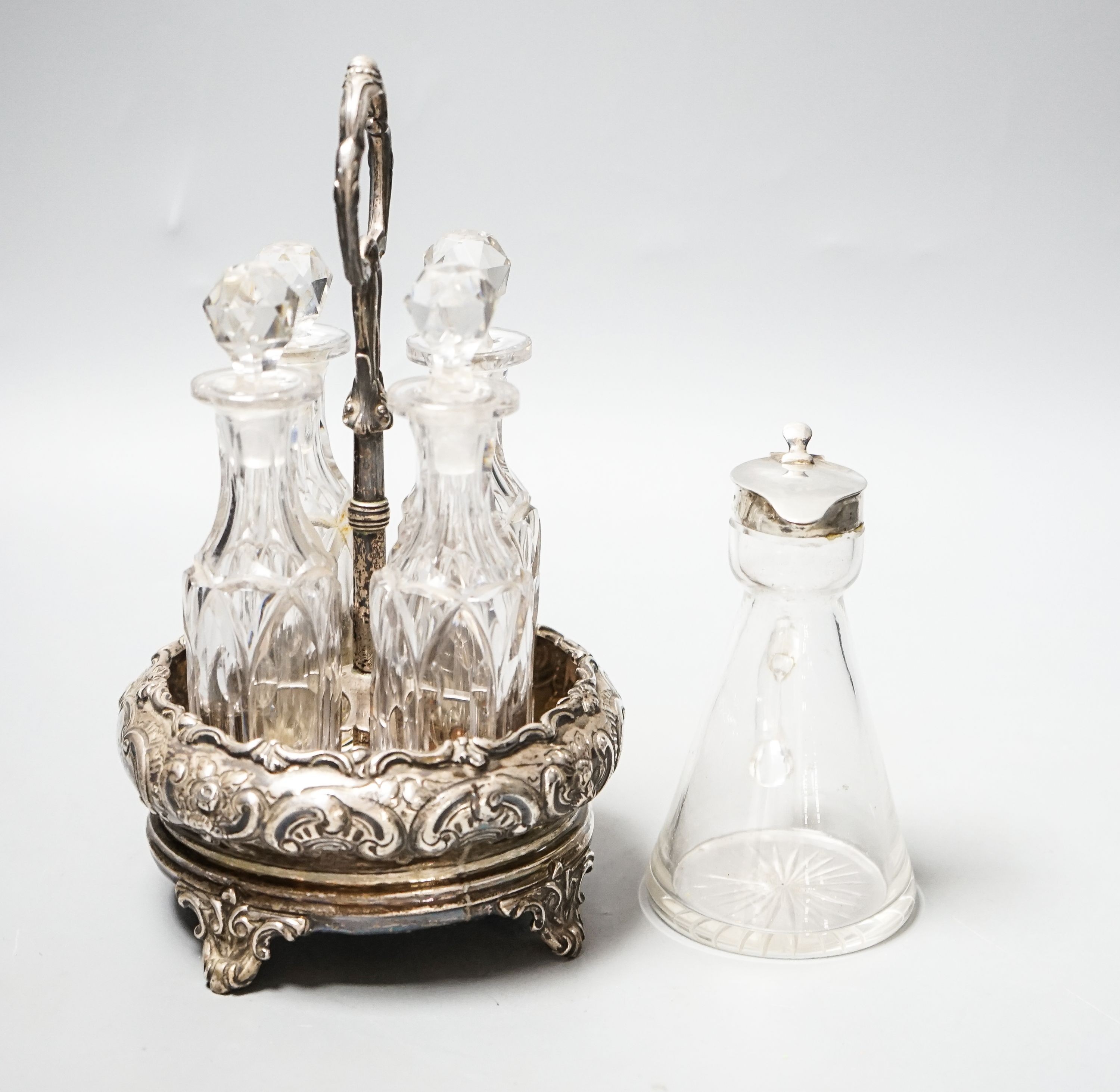 A late Victorian silver circular four division cruet stand, William Evans, London, 1884, height 20.5cm, with four glass bottles, together with a George V silver mounted glass whisky tot jug, Birmingham, 1923.